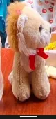 Stuffed Animal Sitting Lion with red ribbbon around neck.