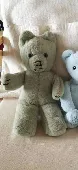 He is a teddy bear about 20 - 30cm tall. Grey / green in colour. Blue eyes. Some
