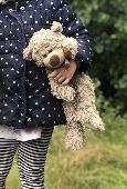 Small brown teddy bear, tatty with a hole above one leg, had a brown/Gold ribbon