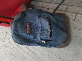 Navy blue jansport bag containg multiple guitar pedals Boss RC 505 and clothes, 