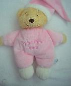 A very old, floppy pink teddy bear with a pink pointed hat, and with the words '