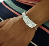 It’s a silver bracelet with a large wing across the front and it’s engraved on t